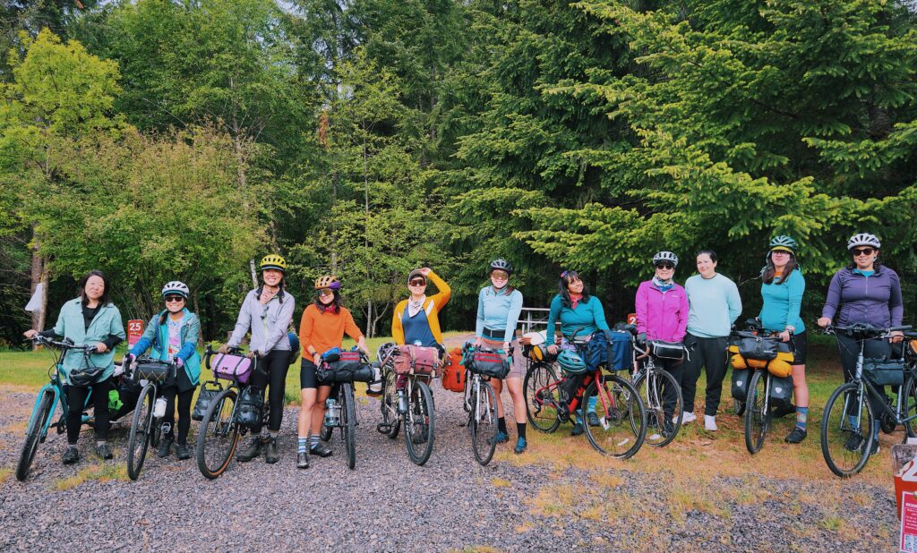 11 people ready for rainy weather smile with their bicycles.