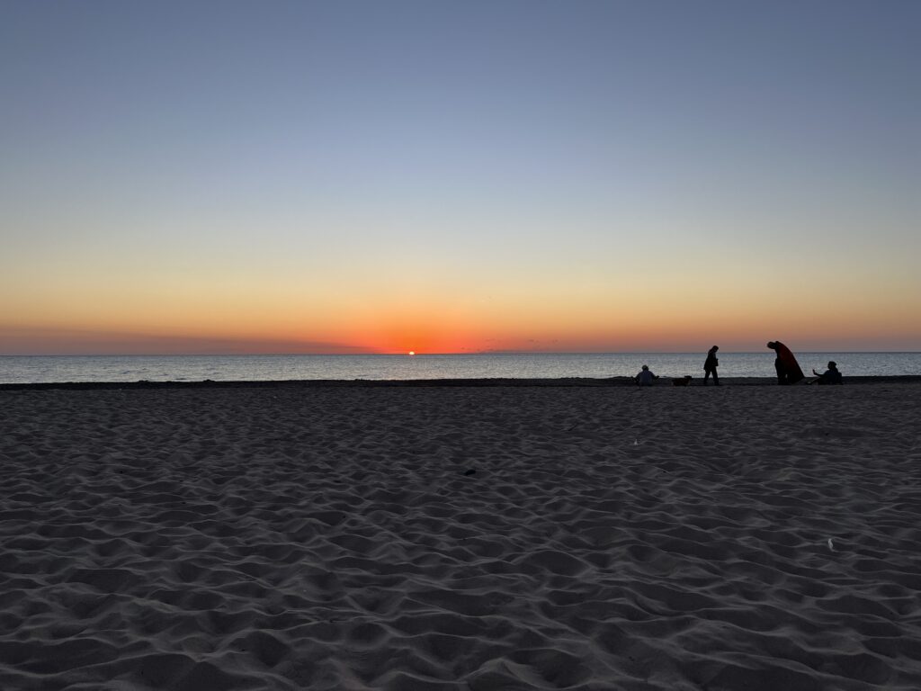 A serene landscape image of the beach at sunset 