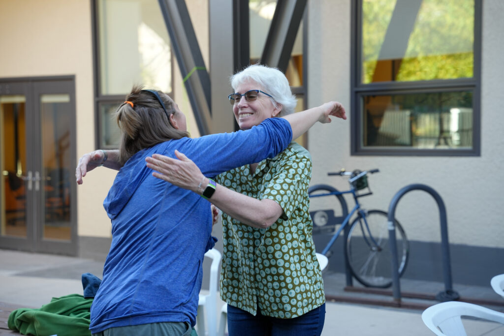 An older woman and a younger woman embrace outside a building.