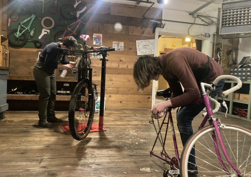 Two people work on bikes in a bike shop 