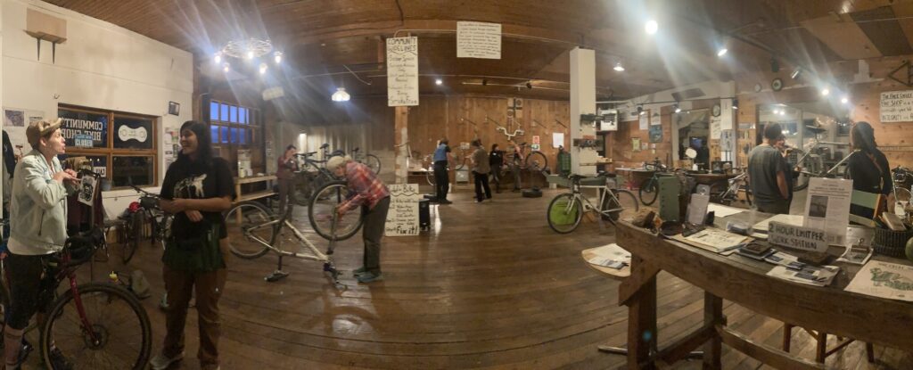 A wide shot of a bike shop where people work on bikes on various stands