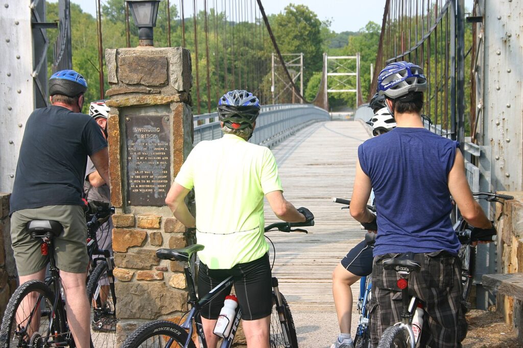 Three men on bikes pause looking forward before entering the bridge